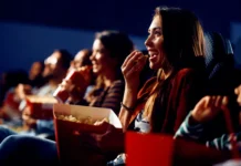 Andare al cinema rende più felici: i risultati dell’esperimento parlano chiaro In foto il pubblico di un cinema che mangia pop-con allegramente.
