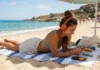 Novità Audible luglio e agosto 2026: le nuove uscite da ascoltare In foto una ragazza che ascolta in spiaggia un audible.